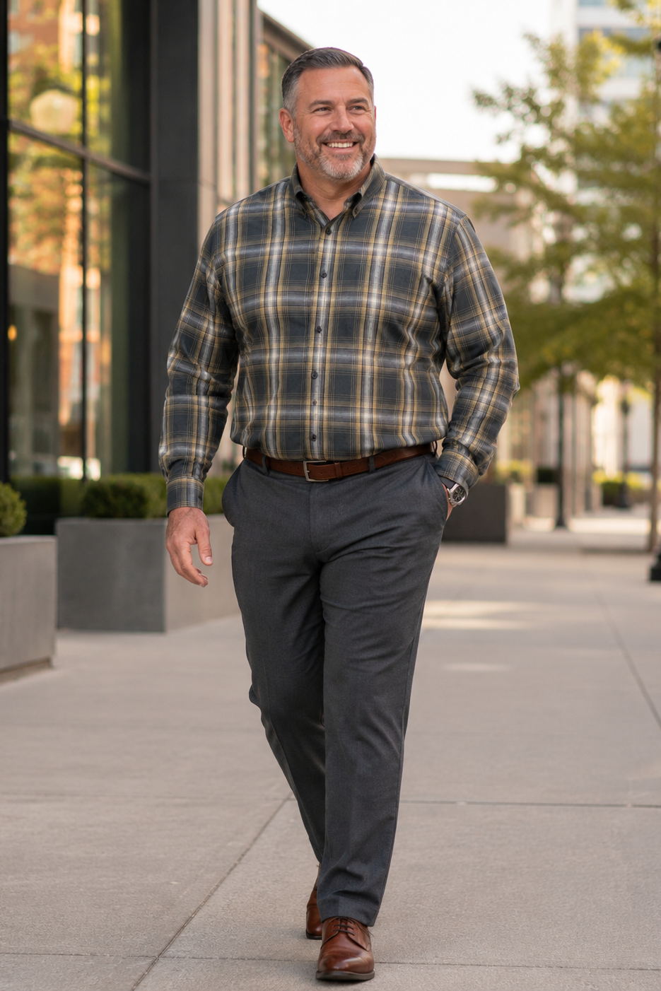 Man walking outdoors wearing a plaid shirt and dark pants.
